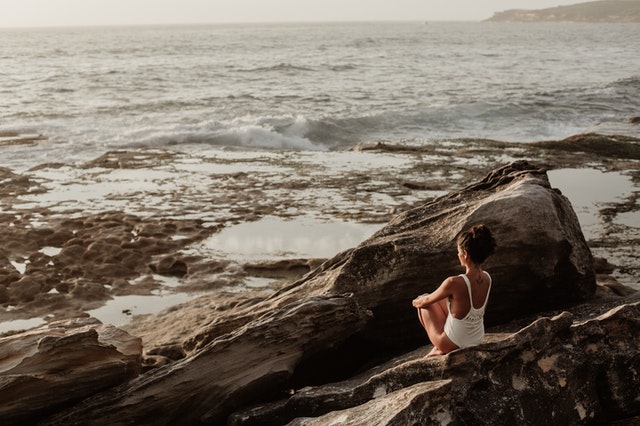Lady sitting on rock near ocean
